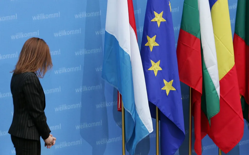 A member of the protocol looks at the flags of (L-R) Luxembourg, the European Union, Bulgaria and Romania during a signing ceremony for the accession treaty of Bulgaria and Romania to the European Union in Luxembourg April 25, 2005. The EU signed an accession treaty with Bulgaria and Romania, embarking on its second wave of enlargement into former communist eastern Europe despite lingering misgivings. The two Balkan states will join the EU on January 1, 2007, provided they implement tough reforms to root out corruption, beef up border controls, strengthen judicial and administrative systems and upgrade rules on state aid to industry.  REUTERS/Francois Lenoir
