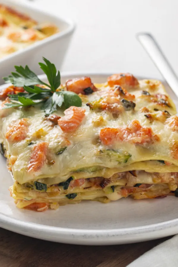 Close up of Lasagna with salmon fish, zucchini, bechamel sauce, parmesan cheese and leek. Baked in oven italian pasta made of flat sheets.