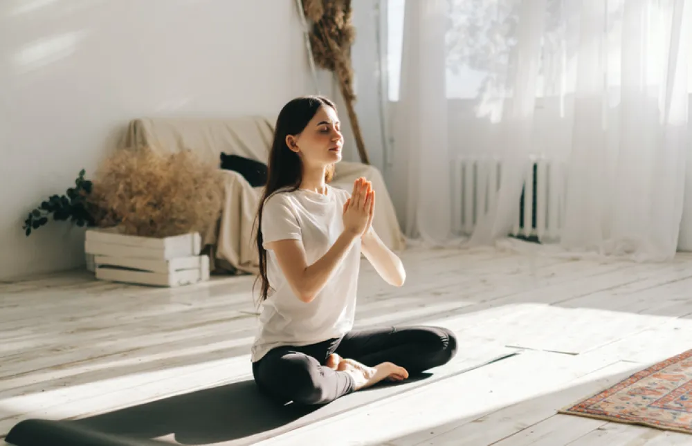 Beautiful brunette fitness woman meditate, doing yoga indoors at home. Staying fit and healthy