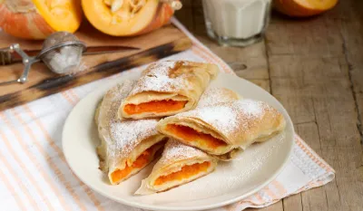 Traditional Romanian or Moldovan pumpkin strudel vertuta served with milk. Rustic style, selective focus.