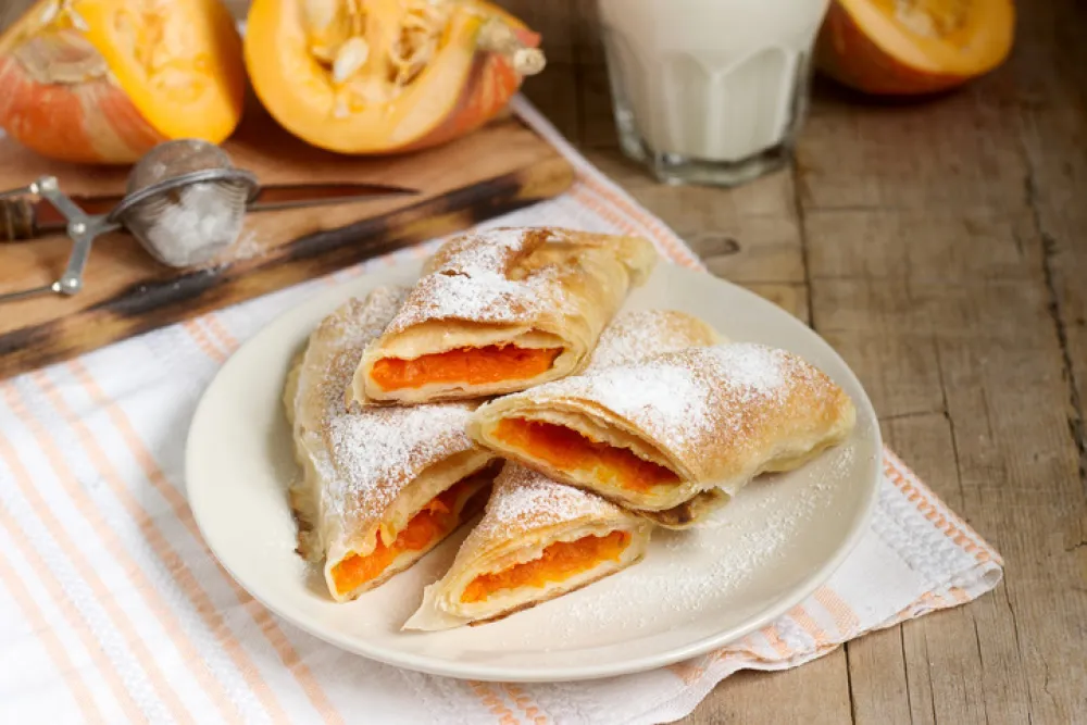 Traditional Romanian or Moldovan pumpkin strudel vertuta served with milk. Rustic style, selective focus.