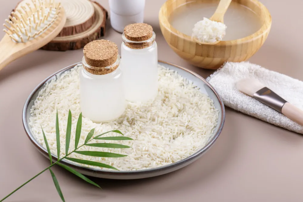 Two bottle with rice water on plate with rice on beige background, healthy beauty treatment ingredients for homemade cosmetics, beauty recipe for home spa, natural skincare preparation