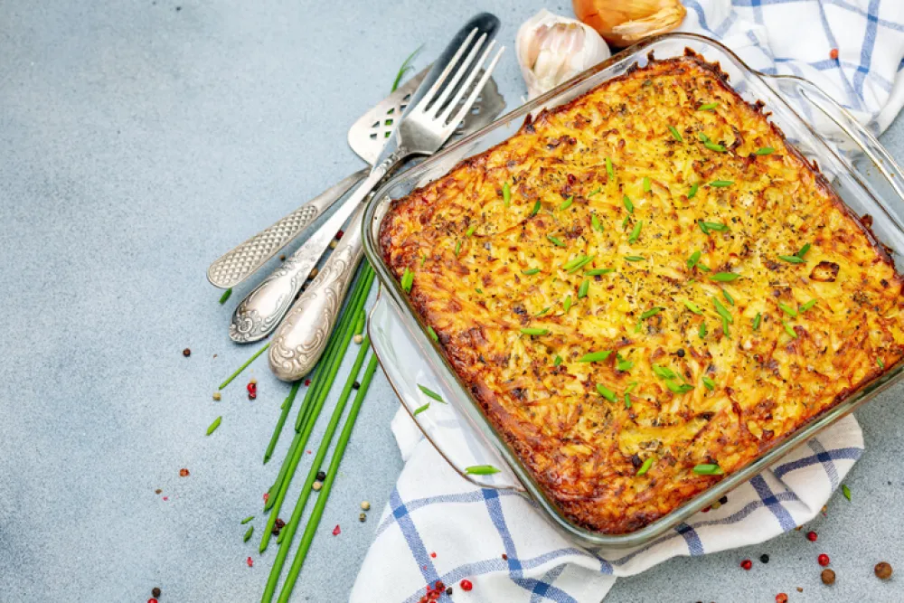 Traditional jewish dish potato kugel with green onions on a textured gray background. Top view.