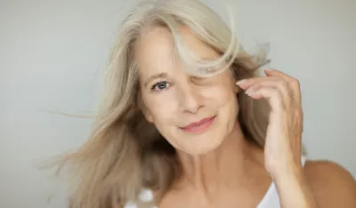 stunning beautiful and self confident best aged woman with grey hair smiling into camera, portrait with white background