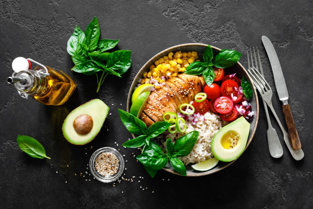 Grilled chicken breast lunch bowl with fresh tomato, avocado, corn, red onion, rice and basil