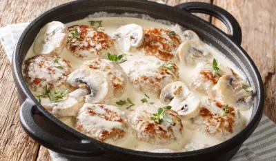 Homemade meatballs cooked with mushrooms served in a creamy sauce with thyme closeup in a pan on the table. horizontal<br>