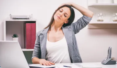 Young businesswoman is relaxing in her office. She is stretching her body.