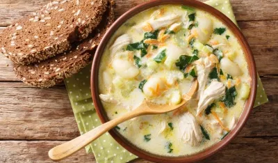 cream soup with gnocchi, chicken and spinach served with bread close-up in a bowl on the table. Horizontal top view from above<br>